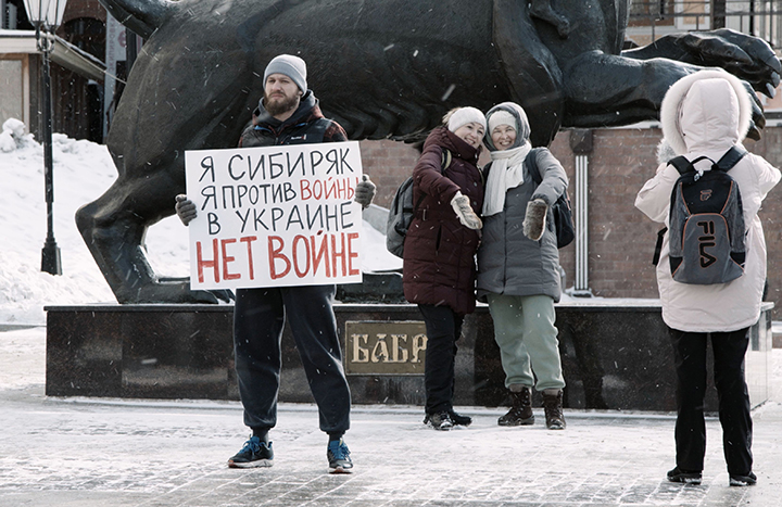 Muž drží transparent s nápisem. Jsem proti válce na Ukrajině.