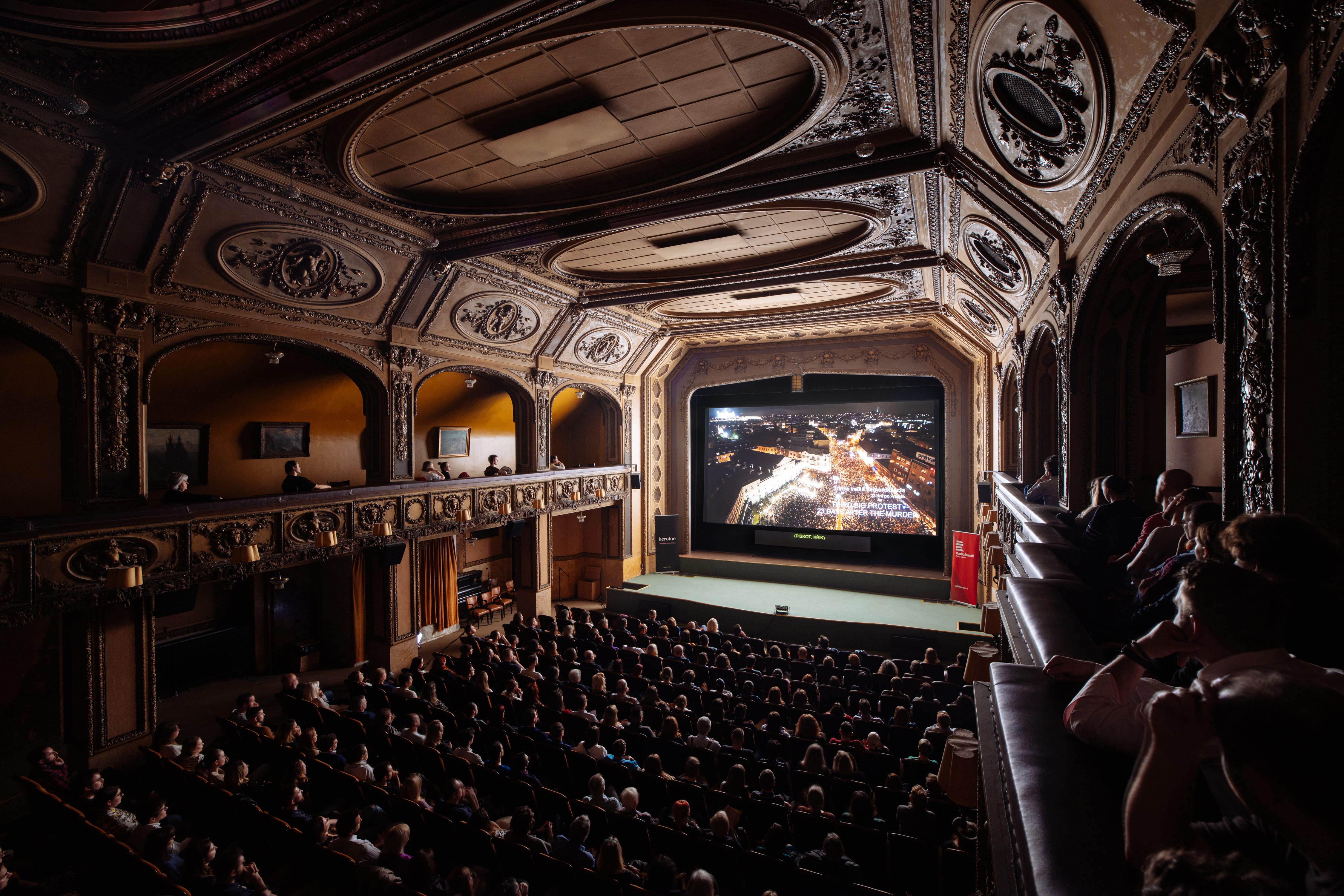 Fotografie z promítání ve velkém sále kině Lucerna. Kino je vyprodané a všichni koukají na plátno.