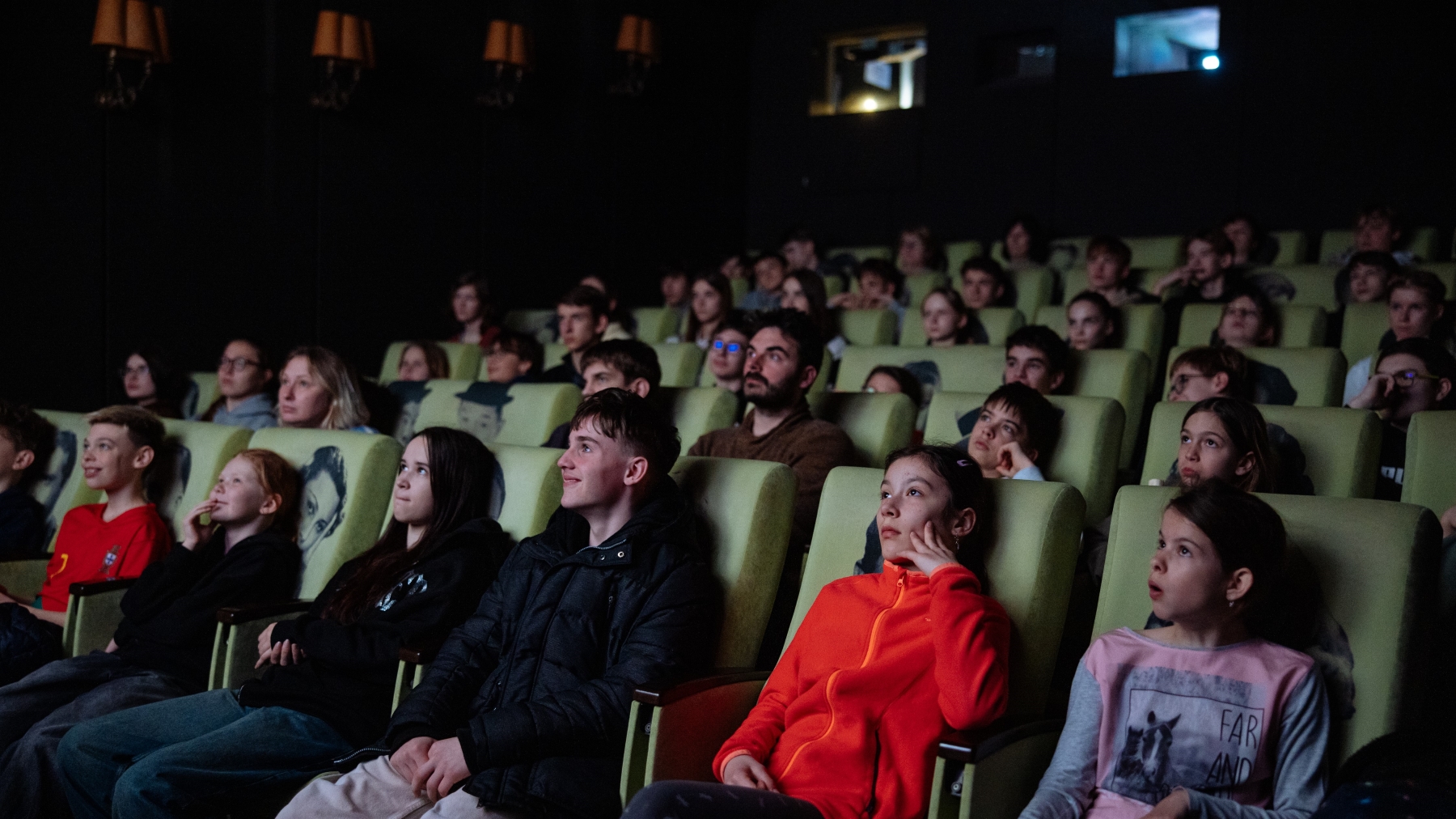 Dětští diváci a jejich učitelé zaujatě sledují film v kinosále.